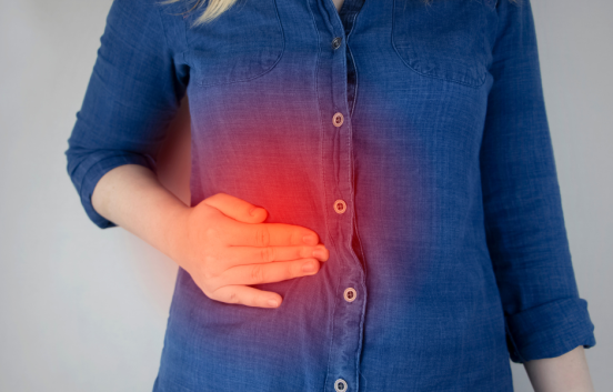Image shows the torso of a woman in a blue shirt. Her hand is on her tummy, over her liver. A red glow indicates liver pain